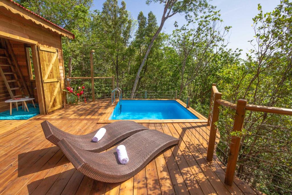 a hammock on a deck next to a swimming pool at Au Jardin Des Colibris Ecolodge&Spa in Deshaies