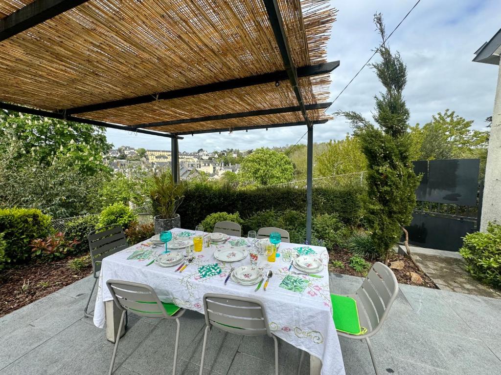 einen Tisch mit einer weißen Tischdecke und Stühlen auf einer Terrasse in der Unterkunft Le Repos des Rias, maison au cœur de la ville in Quimperlé