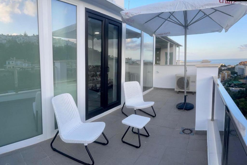 a balcony with two chairs and an umbrella on a building at Verdial 1 Atico in Cala del Moral