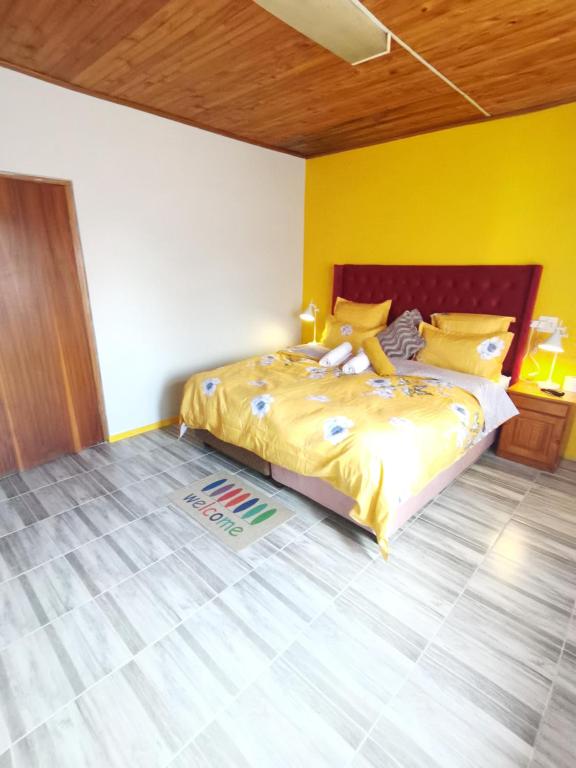 1 dormitorio con 1 cama grande y paredes amarillas en Neo & Ruks Guest house Parow, en Ciudad del Cabo