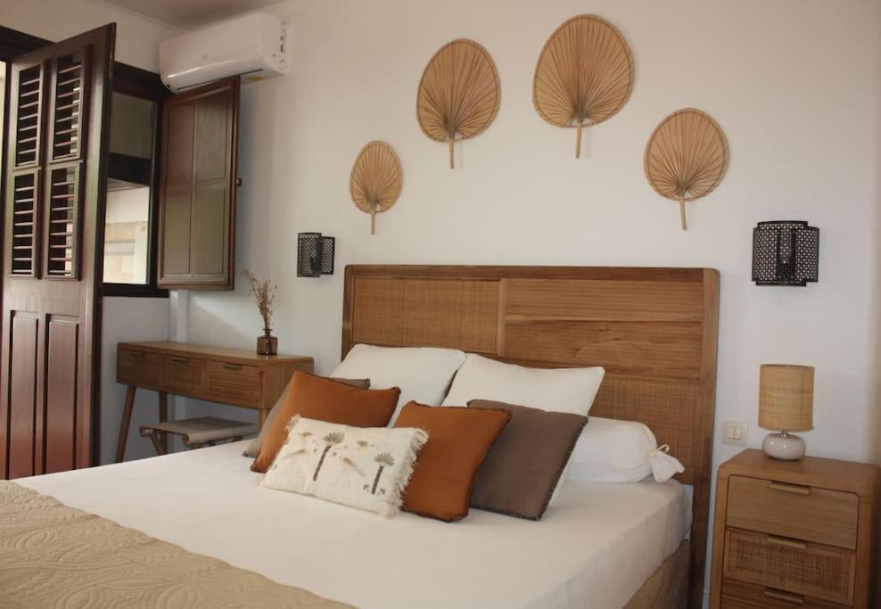1 dormitorio con 1 cama con almohadas marrones y blancas en Parenthèse Créole en Saint-François