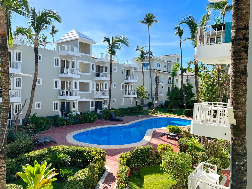 un edificio de apartamentos con piscina y palmeras en SOL CARIBE SUITES - PLAYA LOS CORALES - beach club, wifi, swimming pool en Punta Cana
