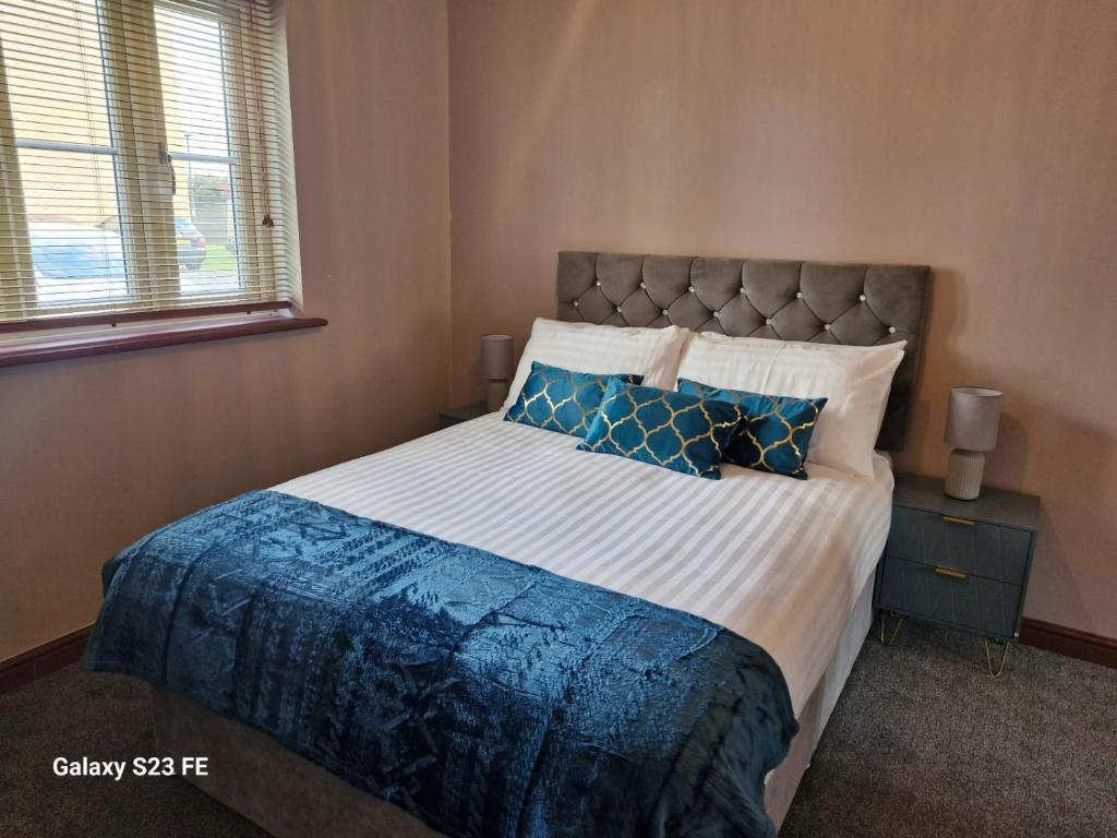 a bedroom with a large bed with blue pillows at LanEnd House in Whiston