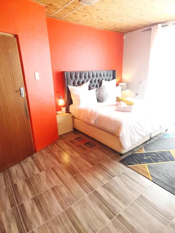 1 dormitorio con 1 cama con pared de color naranja en Neo & Ruks Bellville Guesthouse, en Ciudad del Cabo