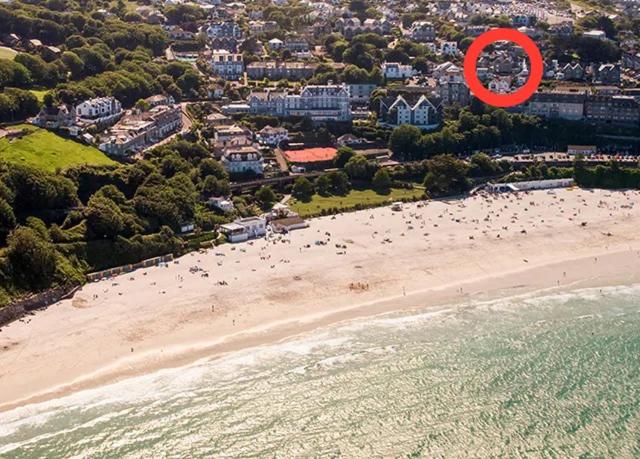 a red frisbee is flying over a beach at ABOVE ST IVES PORTHMINSTER BEACH - "St James Rest" is a REFURBISHED & SUPER STYLISH PRIVATE APARTMENT - King Bedroom with Ensuite, Family Bathroom, Double Bunk Cabin & Sofabed LoungeKitchenDiner - 2 mins walk Main Car Park & Station in St Ives