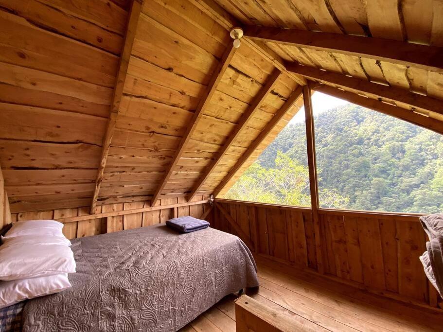 Cama en habitación con ventana grande en Cabaña Alas de Sable Providencia, en Providencia