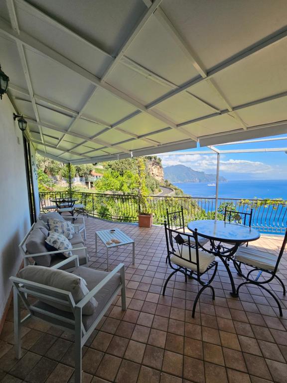 een patio met tafels en stoelen en uitzicht op de oceaan bij Casa Giosuè - Your home on the Amalfi Coast in Conca dei Marini