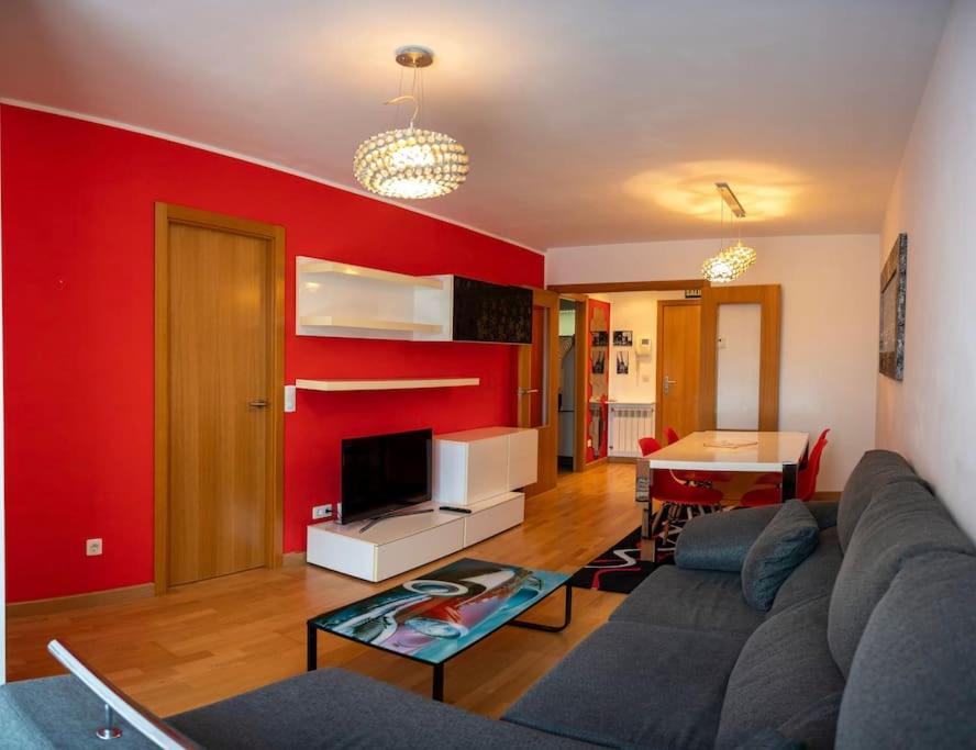 ein Wohnzimmer mit einem Sofa und einer roten Wand in der Unterkunft Piso cerca del Mar con parque infantil y cancha de baloncesto in Santa Cruz de Bezana