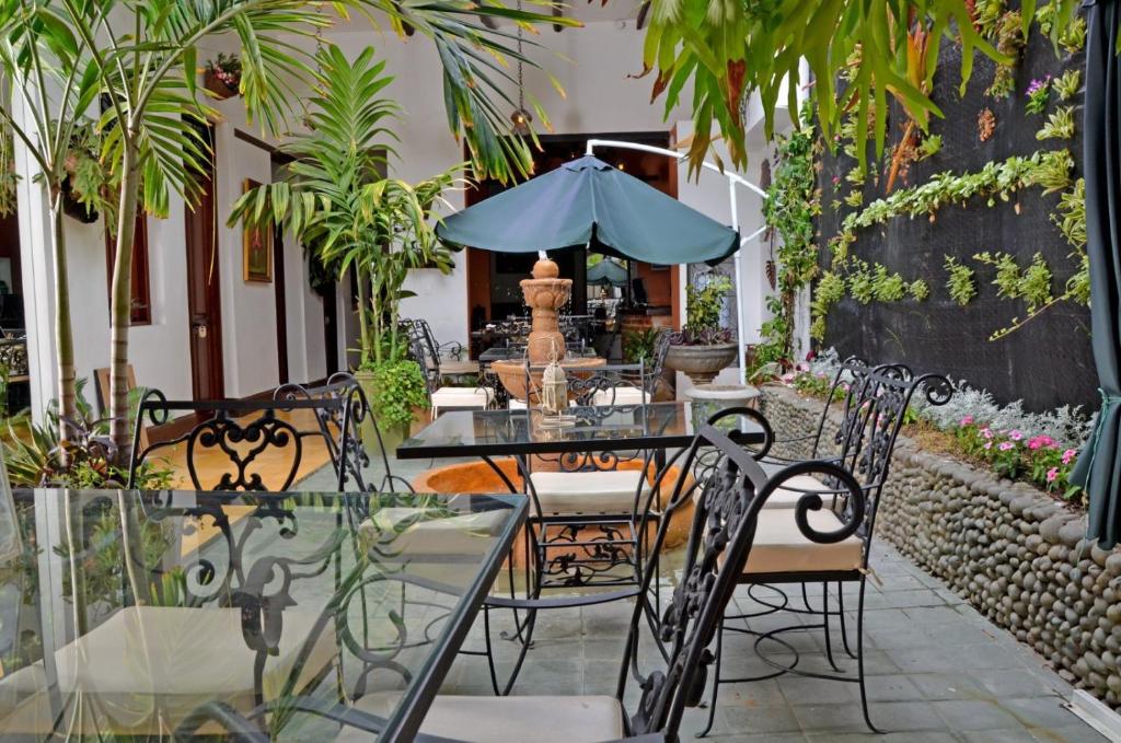 eine Terrasse mit einem Tisch und Stühlen mit einem Sonnenschirm in der Unterkunft Boutique Portón De Granada in Cali