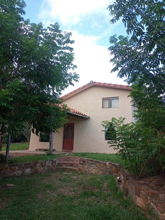 a white house with a red door in a yard at Casa Loto in Samaipata