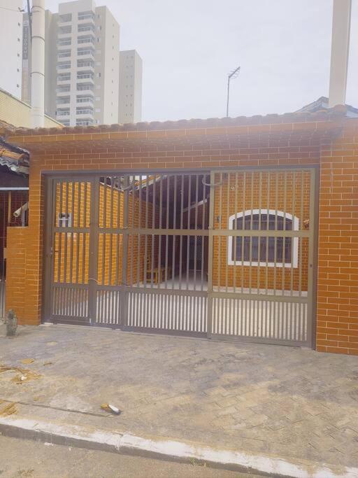 een oranje bakstenen gebouw met een poort en ramen bij Casa a meia quadra da Praia do Caiçara PG in Solemar