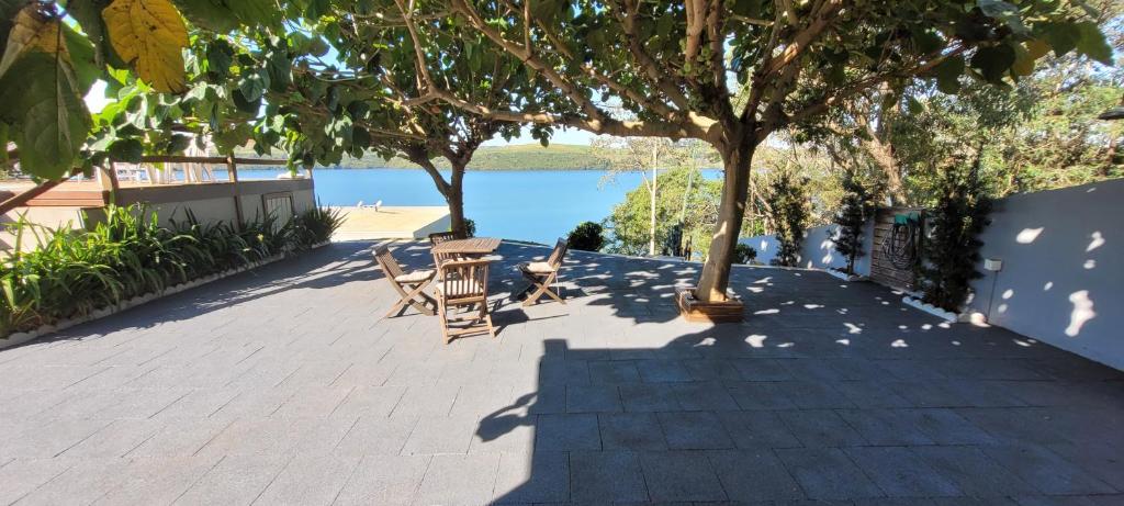 een patio met een tafel en stoelen naast het water bij Casa Marinas Boa Vista Pr. in Boa Vista Parecida