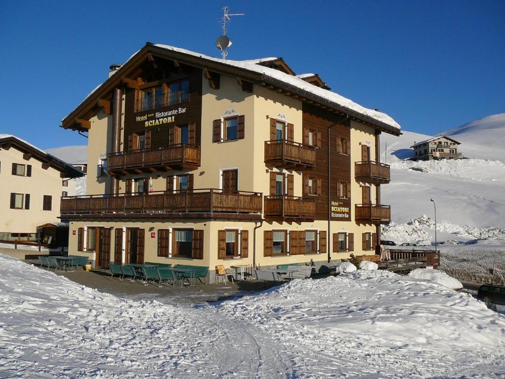 duży budynek na szczycie pokrytej śniegiem góry w obiekcie Hotel Sciatori w Livigno