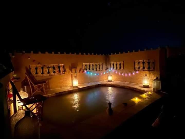 a swimming pool at night with candles and lights at غزاله كامب in Siwa