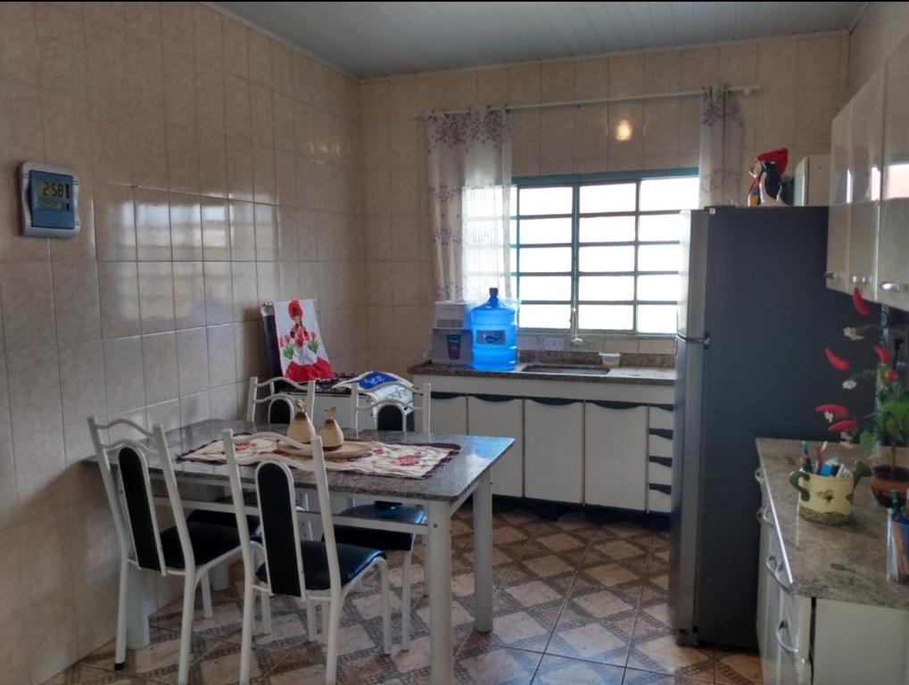 a kitchen with a table and a refrigerator at Pousada Malu in Bragança Paulista