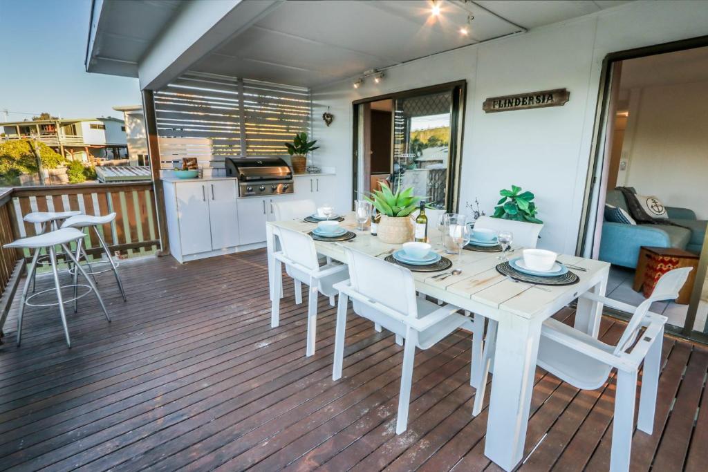 a white dining table and chairs on a deck at A Lure - A 2-minute walk to the pristine beach! in Agnes Water