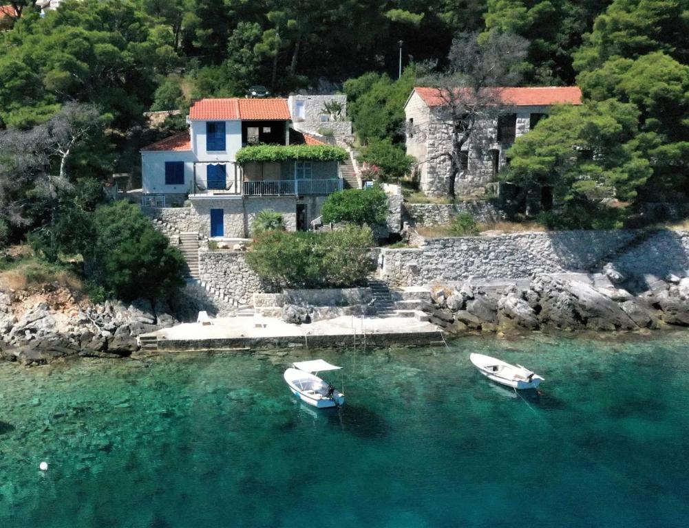 two boats in the water in front of a house at Apartments by the sea Sobra, Mljet - 22329 in Babino Polje