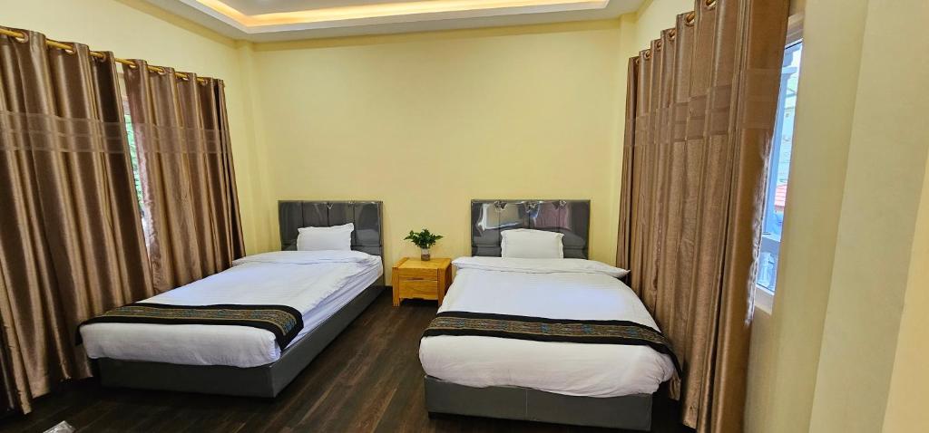 two twin beds in a room with a window at Yula Hotel Thatluang in Vientiane