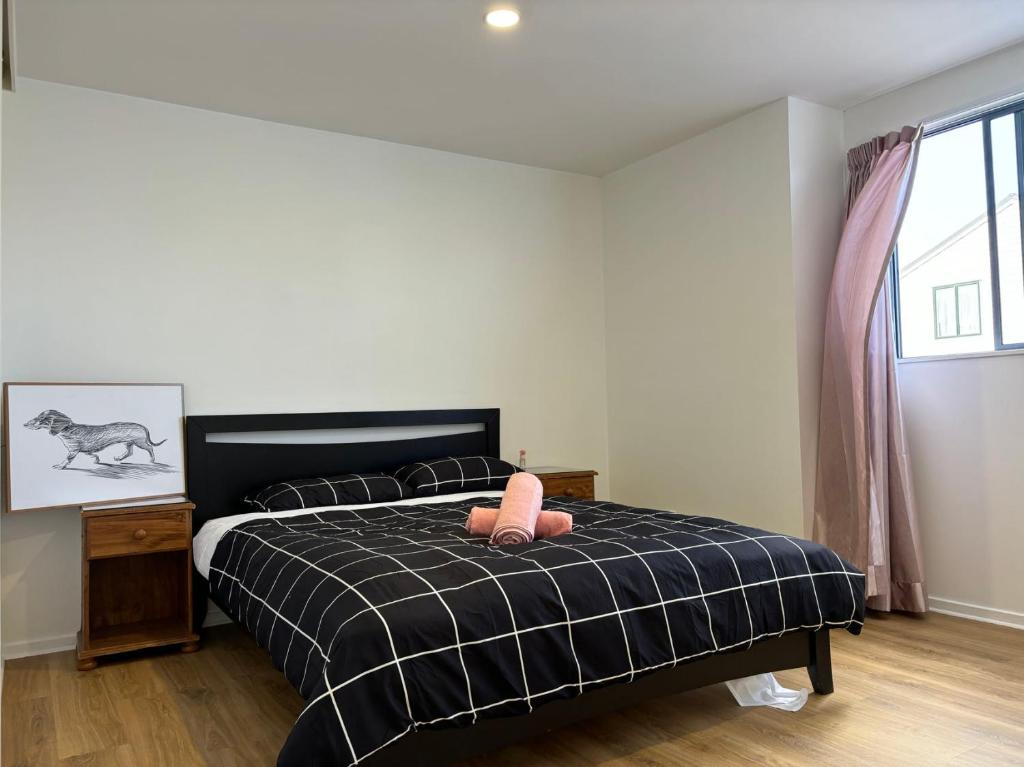 um quarto com uma cama com uma almofada cor-de-rosa em New Lynn Tidy House em Auckland