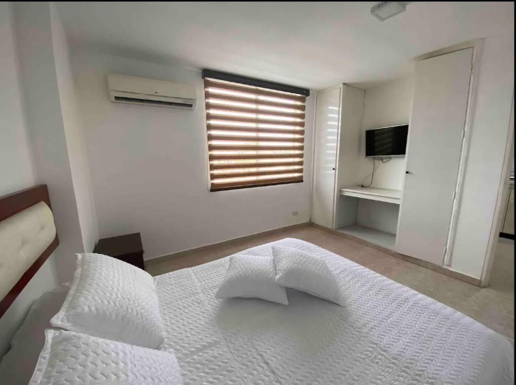 1 dormitorio con cama blanca y ventana en Apartamentos Sur de Cali cerca a Unicentro - 402 en Cali