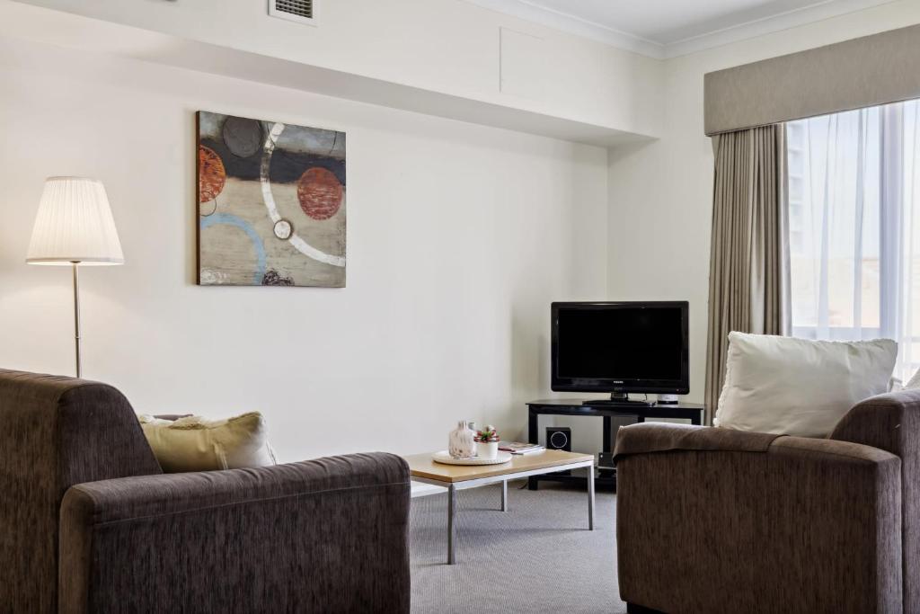 a living room with two chairs and a flat screen tv at Urban Apt in the Heart of Northbridge in Perth