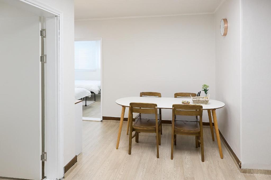 a white dining room with a table and chairs at Ogeum stay in Seoul