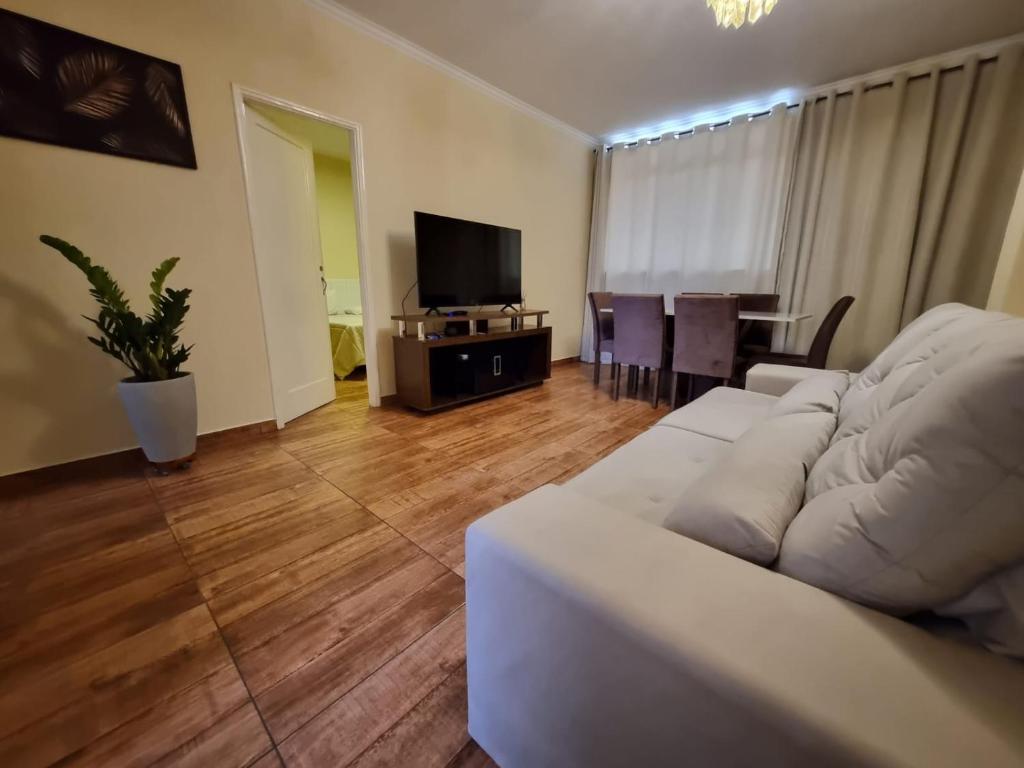 un soggiorno con divano bianco e TV di Apart Roma l Amplo e confortável no Centro de Águas de Lindóia ad Águas de Lindóia