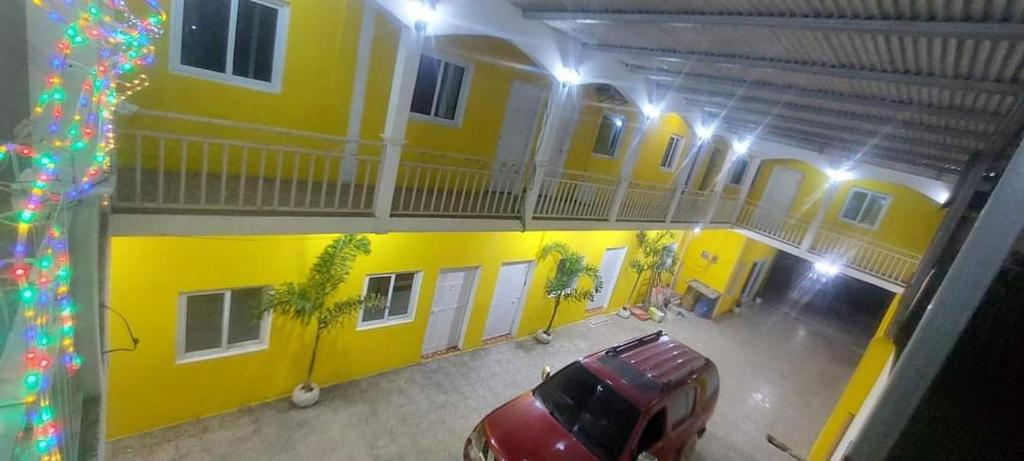 een auto geparkeerd voor een geel gebouw bij Hotel La Posada de Don Chusito in Puerto Barrios