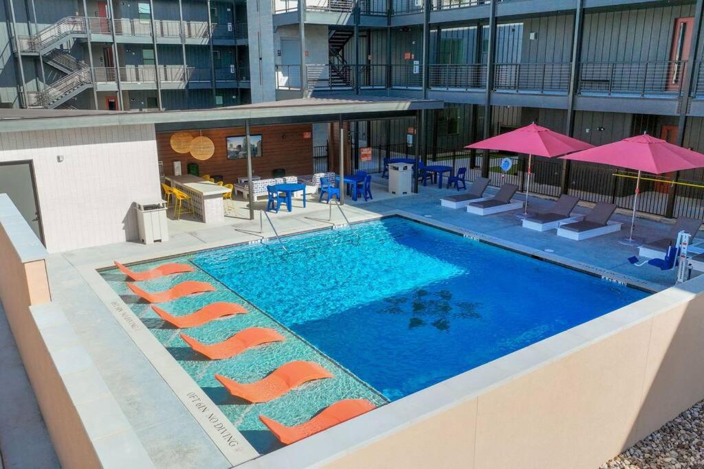 a swimming pool with chairs and umbrellas on a building at Luxury Condo in Prime Location (Pet-Friendly) in New Braunfels