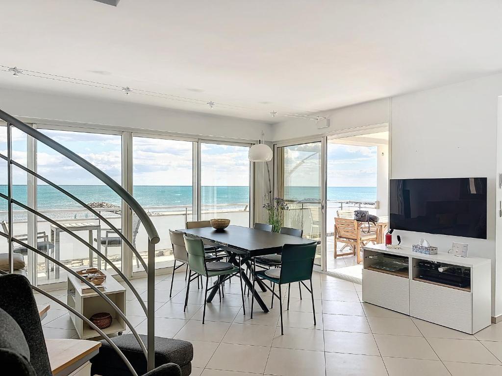 une salle à manger avec une table et une vue sur l'océan dans l'établissement Appartement climatisé avec terrasse et parking, face à la mer - FR-1-715-76, à Mauguio