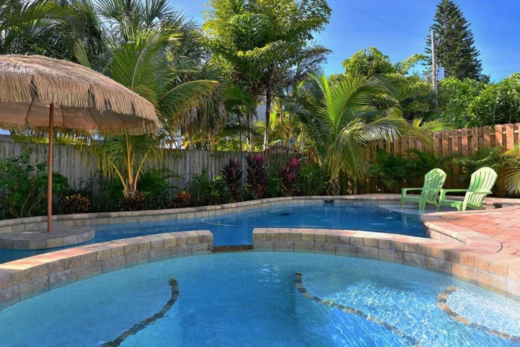 una piscina en un patio con sillas y árboles en Time for the Sea - Holmes Beach, FL, en Holmes Beach