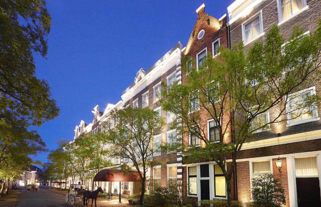 a building on a street with trees in front of it at Hotel Amsterdam Huis Ten Bosch in Sasebo