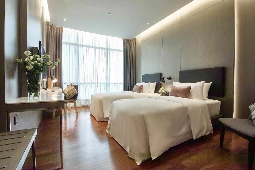 A bright twin room has two separate beds and a full-height window.