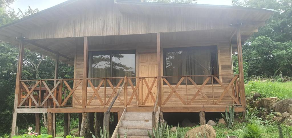 uma casa de madeira com um grande alpendre e janelas em Cabaña Palo Verde em Puntarenas