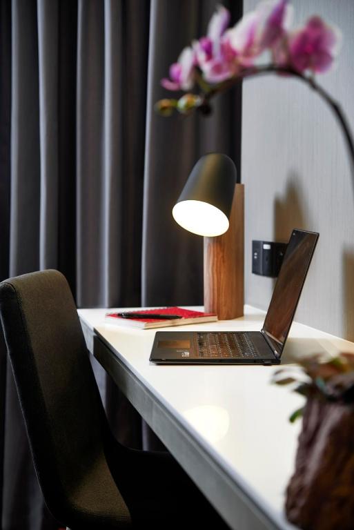 A compact desk workspace is set beside dark curtains with a laptop and task lamp.