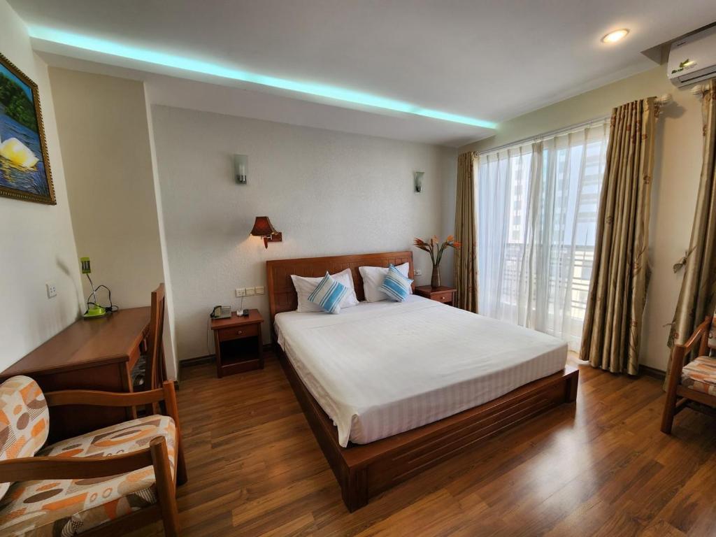 1 dormitorio con cama, escritorio y ventana en Golden Sea Hotel, en Nha Trang