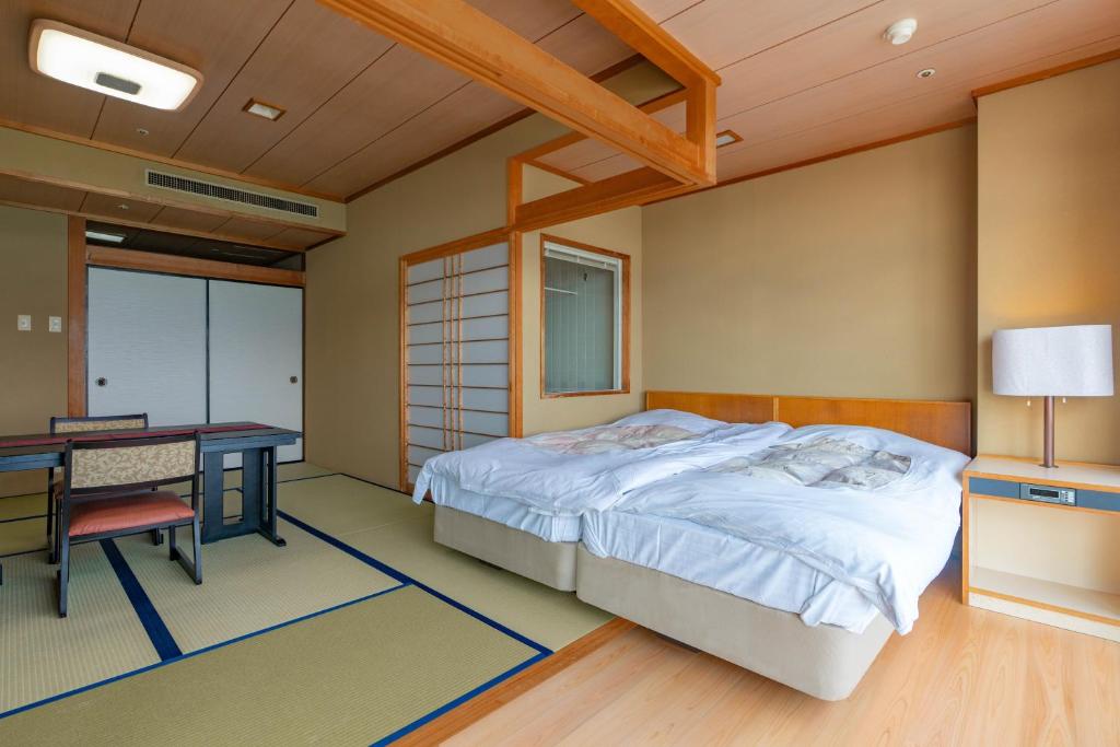 a bedroom with a bed and a desk and a table at Atagawakan in Higashiizu