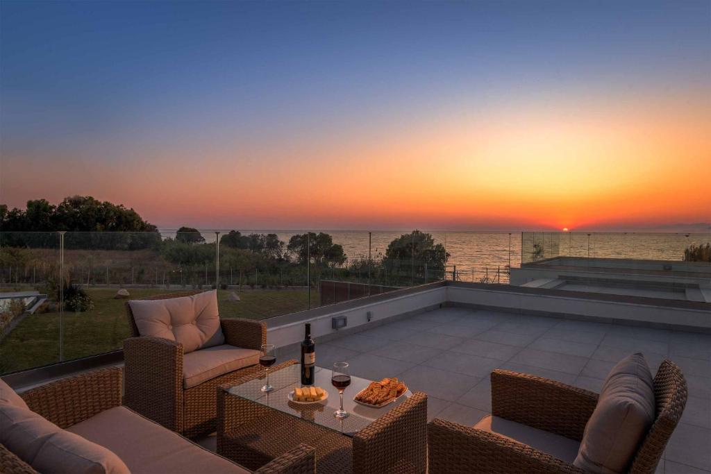 un patio con sillas y una mesa con puesta de sol en Villa Panaxia Akte, en Theologos