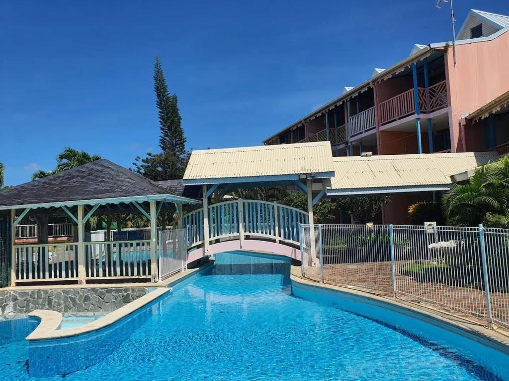 a swimming pool with a gazebo next to a building at Studio agréable à Sainte-Anne de 30 m² avec piscine partagée in Sainte-Anne