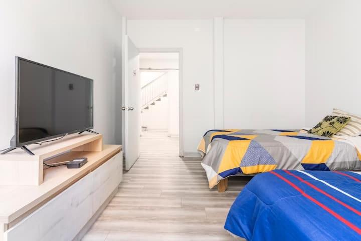 een slaapkamer met een flatscreen-tv en een bed bij hostal mancora monjitas 755 in Santiago