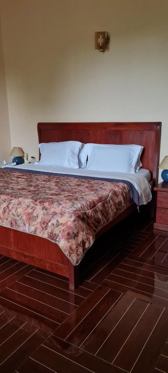 ein großes Bett in einem Schlafzimmer mit einem Kopfteil aus Holz in der Unterkunft Kaole Cosy Retreat in Bagamoyo