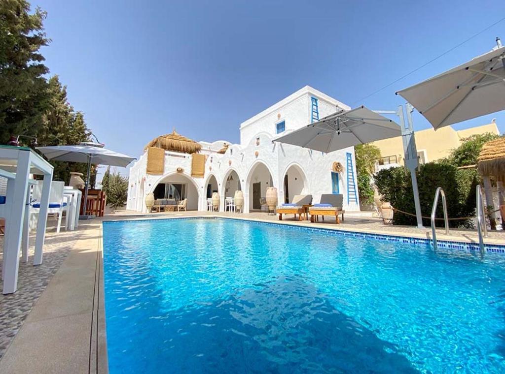 a swimming pool in front of a house at Villa Calma - Vue Mer in Al Ḩaddādah