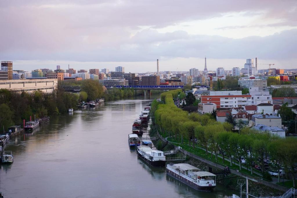 Un río con barcos estacionados junto a una ciudad en Charming 63 m2 apt with views of the Eiffel Tower, en LʼÎle-Saint-Denis