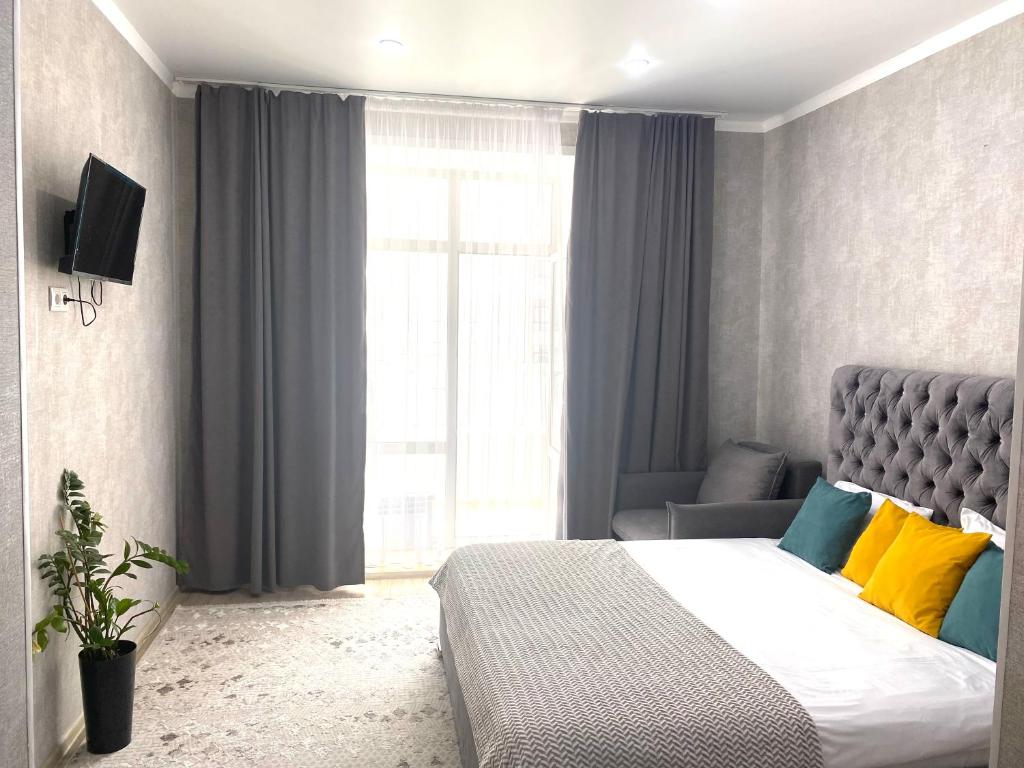 um quarto com uma cama, um sofá e uma janela em Комфортные апартаменты на ЭКСО em Prigorodnyy