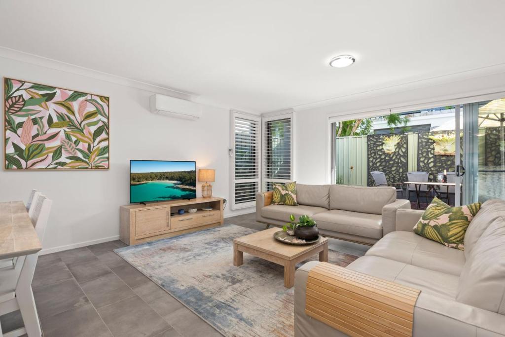 a living room with a couch and a tv at Inish by Experience Jervis Bay in Huskisson