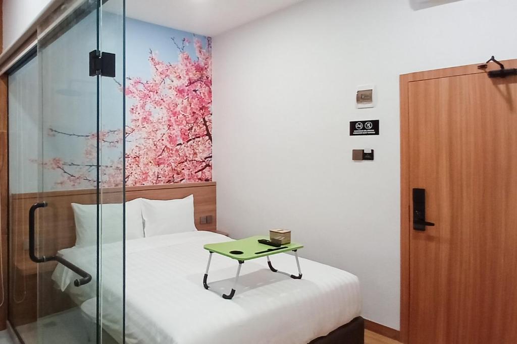 um quarto com uma cama e uma cabina de duche em vidro com uma mesa em Urbanview Hotel R House Batuaji em Kubuk