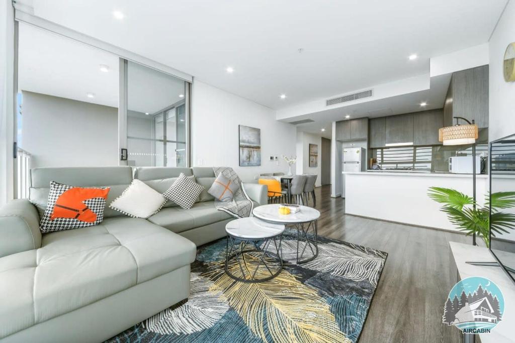 een woonkamer met een bank en een tafel bij Aircabin - Burwood - Modern Comfy - 2 Beds Apt in Sydney