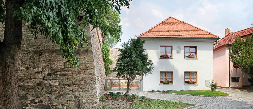 a white house with two windows and a brick wall at Penzion Dobré Časy in Poděbrady