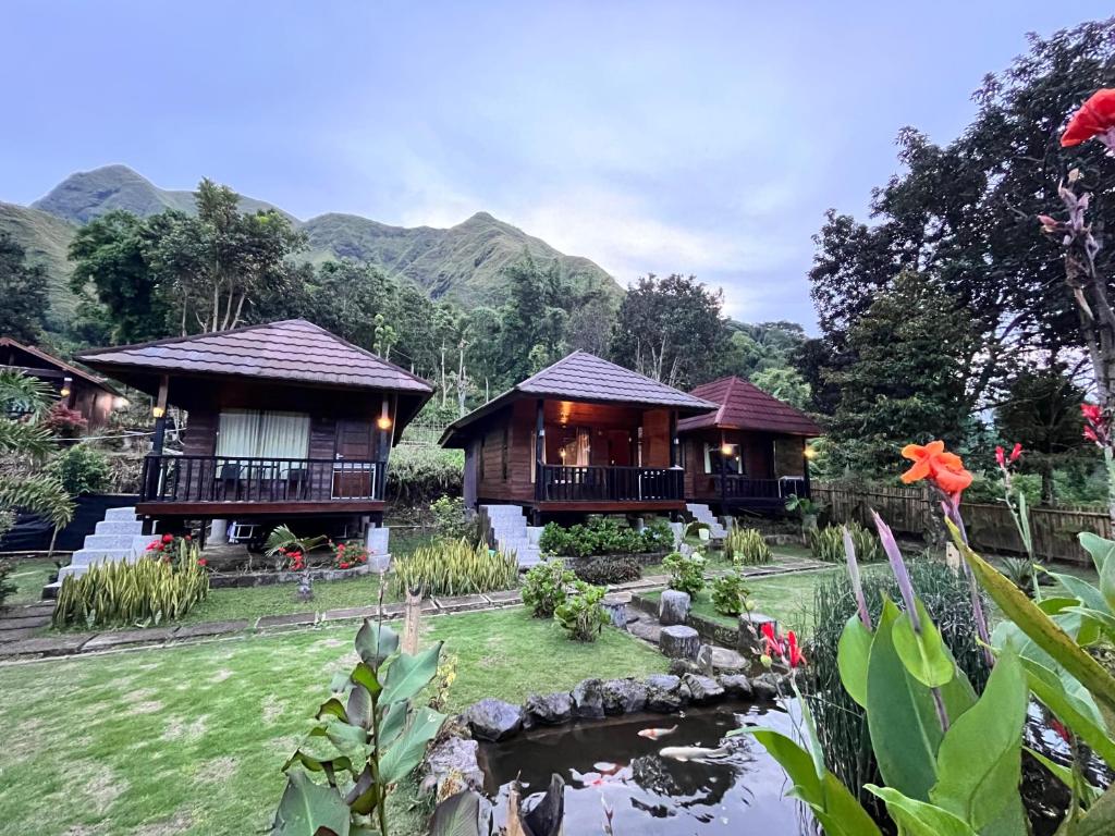 ein paar Cottages mit einem Teich davor in der Unterkunft Sembalun Kita Cottage in Sembalun Lawang