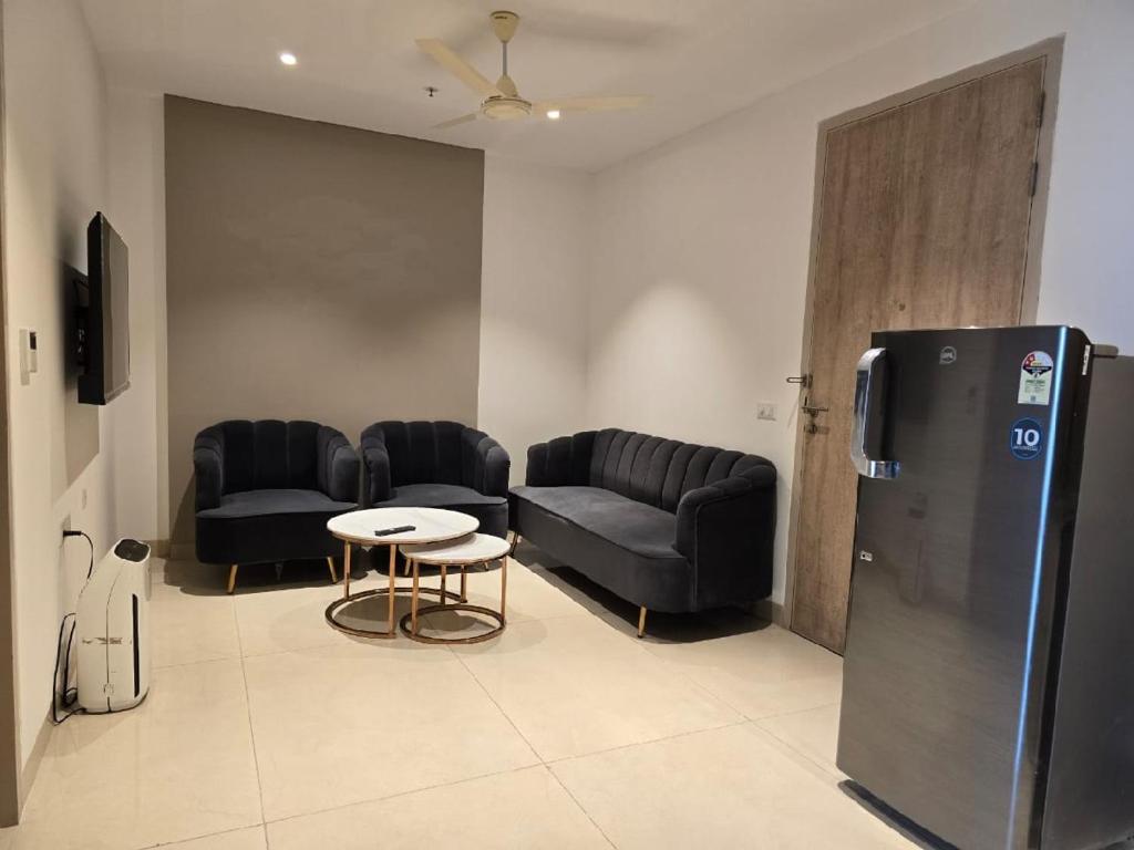 Cette chambre dispose de canapés, d'une table et d'un réfrigérateur. dans l'établissement Lifestyle studios, à Gurgaon